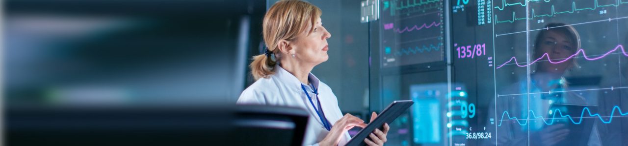 Healthcare professional examining cardiac event monitoring data and taking notes on tablet.