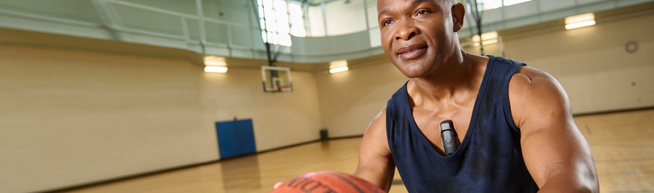 Man on basketball court while wearing device.