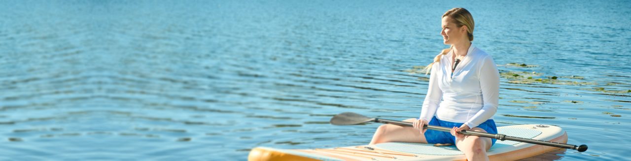 Woman on a kayak on the lake, wearing the BodyGuardian Remote Cardiac Monitor.